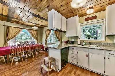 a kitchen with white cabinets and a table and chairs at Bear Haus - Sledding At Cabin - Forest Views - Foosball in South Lake Tahoe