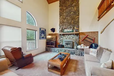 a living room with a couch and a stone fireplace at Bearfoot Getaway in Shaver Lake