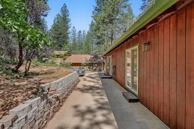 a walkway next to a building with a stone wall at Great Cabin with AC Firepit Fireplace in Arnold