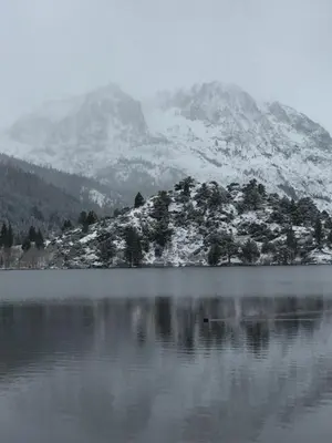 a mountain with snow on top of a lake at Whispering Pines in June Lake