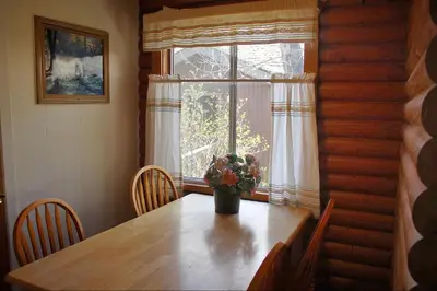 a dining room table with a vase of flowers on it at Whispering Pines in June Lake