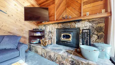 a living room with a stone fireplace with a tv at Mammoth Sierra Townhomes #38 condo in Mammoth Lakes