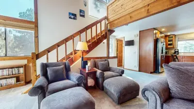 a living room with two chairs and a staircase at Mammoth Sierra Townhomes #38 condo in Mammoth Lakes