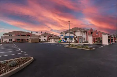an empty parking lot with a cloudy sky in the background at Orchard Parks in Tracy