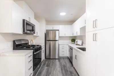 a kitchen with white cabinets and a stainless steel refrigerator at Orchard Parks in Tracy