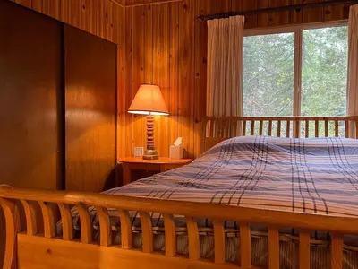 a bedroom with a bed and a lamp and a window at Groovy Cabin in the Woods in Pollock Pines