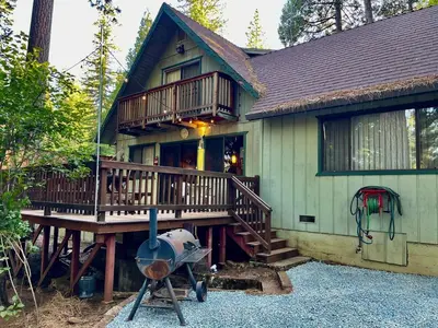 a house with a large deck and a grill at Groovy Cabin in the Woods in Pollock Pines