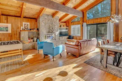 a living room with a stone fireplace in a log cabin at Cozy Carnelian Bay Escape with Deck and Foosball in Carnelian Bay
