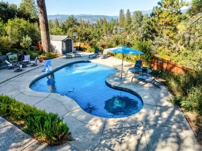an overhead view of a swimming pool with an umbrella at Spacious Mountain View Oasis - Pool, Spa & Game Rm in Oakhurst