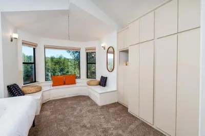 a bedroom with white walls and windows and a couch at Spacious Mountain View Oasis - Pool, Spa & Game Rm in Oakhurst