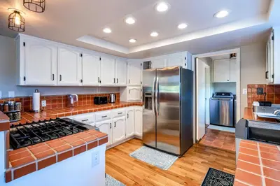 a kitchen with white cabinets and a stainless steel refrigerator at Spacious Mountain View Oasis - Pool, Spa & Game Rm in Oakhurst