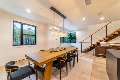 a dining room with a table and chairs and a staircase at Spectacular New 4BR Townhome: Garage, Jacuzzi, BBQ in Mammoth Lakes