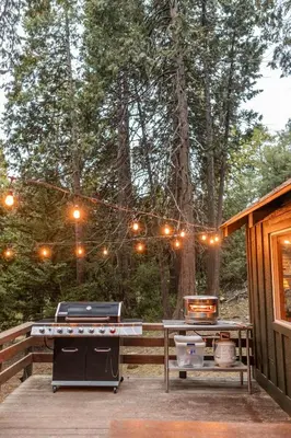 a grill on a deck next to a cabin at BunkHouse 1960's Camp Vibe with Timeless Wet Bar in Springville