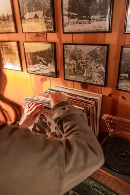 a person reading a magazine in a room with pictures on the wall at BunkHouse 1960's Camp Vibe with Timeless Wet Bar in Springville