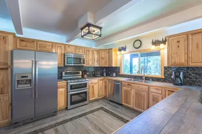 a kitchen with wooden cabinets and stainless steel appliances at Luxurious Yosemite Pines Lodge, Pool, Spa, Ponies, Views in Mariposa