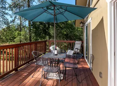 a table and chairs on a deck with an umbrella at Luxurious Yosemite Pines Lodge, Pool, Spa, Ponies, Views in Mariposa