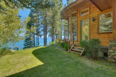 a wooden house with a porch and a door at Rubicon Bay Lakefront by Tahoe Getaways - 4BR with Bonus Room, Private Pier, Buoy & Beach Access in Tahoma