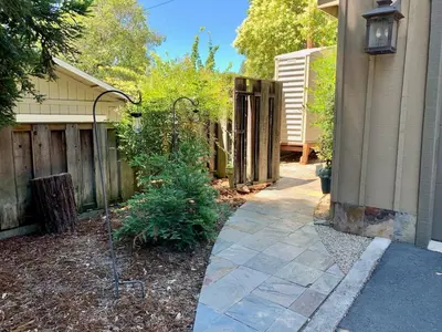 a walkway leading to a house with a fence at King Bed-Peaceful Modern Cottage-Garden Setting in Carmichael