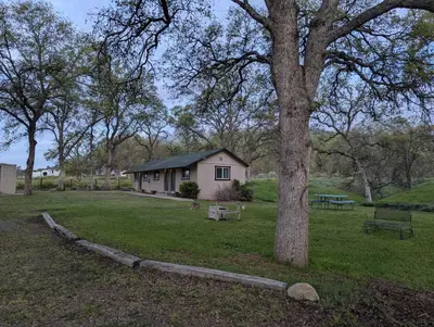 a small house in a field next to a tree at Squaw Valley Motel Room 7 in Dunlap