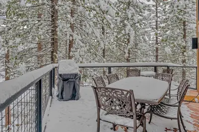 a table and chairs on a deck covered in snow at Luxury Truckee Retreat with Hot Tub and Sauna in Truckee