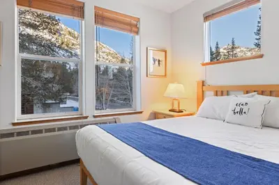 a bedroom with a bed and two large windows at Palisades Tahoe Lodge Rentals Premium Fireplace One Bedroom #807 in Olympic Valley