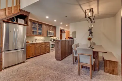 a kitchen with wooden cabinets and a table and chairs at Palisades Tahoe Lodge Rentals Premium Studio Loft #358 in Olympic Valley