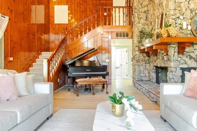 a living room with a piano and a stone wall at The Grand Waterside Estate Easy drive to Yosemite in Modesto