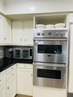 a kitchen with white cabinets and a stainless steel oven at The Grand Waterside Estate Easy drive to Yosemite in Modesto