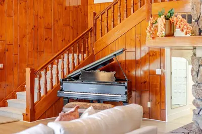 a living room with a piano next to a staircase at The Grand Waterside Estate Easy drive to Yosemite in Modesto