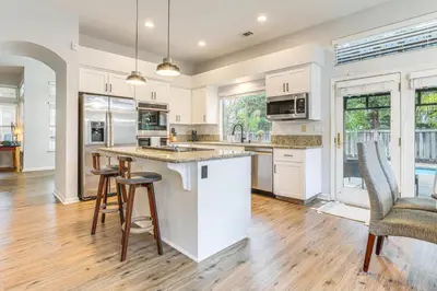 an open kitchen with white cabinets and bar stools at Family Home Near Folsom Lake in El Dorado Hills! in El Dorado Hills