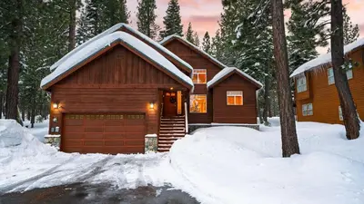 a log cabin in the snow with a garage at Pinewood Lodge by AvantStay Cozy Cabin Near Ski Resorts Hiking in Truckee