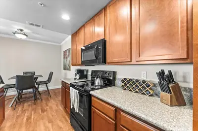 a kitchen with wooden cabinets and a black stove top oven at New Stylish 1BR Apt with Heated Pool Gym & Yoga Studio in Reno