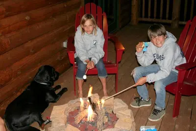 a man and a girl and a dog sitting around a fire at Family-Friendly Log Cabin Rental in California's Gold Country near Sacramento in Volcano