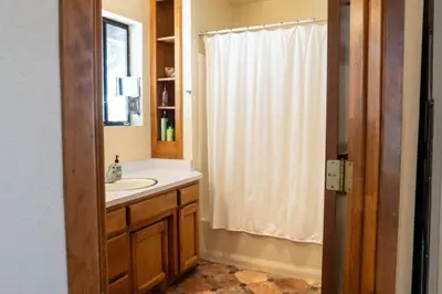 a bathroom with a sink and a white shower curtain at Blue Jay's Nest Sequoia Cabin in Ponderosa, CA in Ponderosa