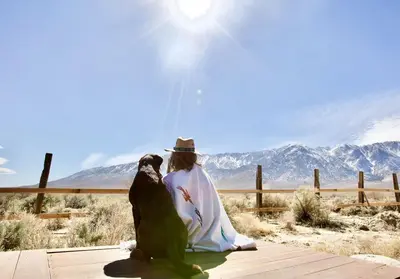 a woman sitting next to two birds on a boardwalk at Stunning Design Rental Incredible for a Luxury Escape in Lone Pine, California in Lone Pine