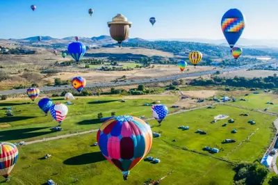 a bunch of hot air balloons flying over a field at New Trendy 1BR Apartment with Heated Pool Gym & Minigolf in Reno