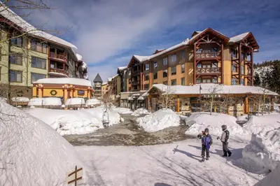 two people standing in the snow in front of a lodge at Summit 295 in Mammoth Lakes