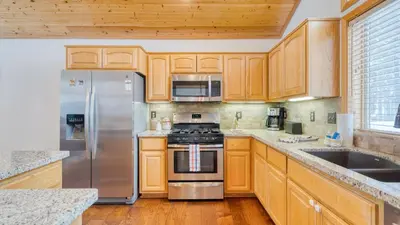 a kitchen with wooden cabinets and stainless steel appliances at Oslo Haus by AvantStay Cabin Retreat Near Northstar Downtown Truckee in Truckee
