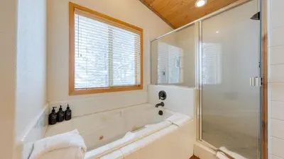 a bathroom with a tub and a glass shower at Oslo Haus by AvantStay Cabin Retreat Near Northstar Downtown Truckee in Truckee