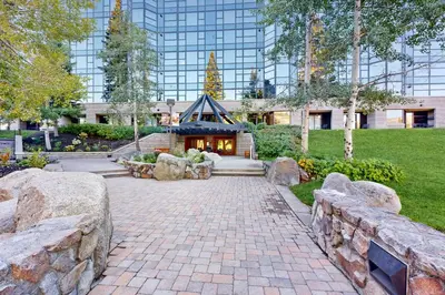 a garden with a building in the background with a stone wall at Ski-InandSki-Out and Mtn Views! Everline Resort Condo in Olympic Valley