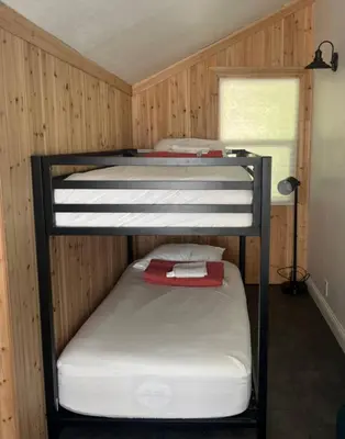 two bunk beds in a room with wooden walls at My Side of the Mountain Rest Recharge Repeat in Shaver Lake