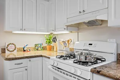 a kitchen with white cabinets and a stove top oven at Midtown Apartment with Private Parking and King Bed in Sacramento