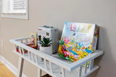a white shelf with books and toys on it at Midtown Apartment with Private Parking and King Bed in Sacramento