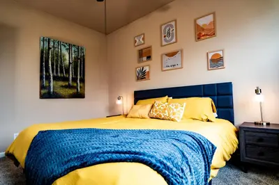 a bedroom with a large bed with a blue blanket at Eat-Sleep-Stroll-Repeat! Walkable Midtown 2BR Home in Reno