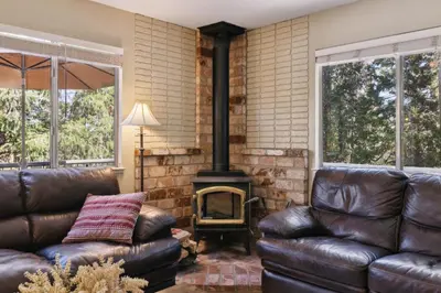 a living room with leather couches and a wood stove at Whispering Pines Retreat home in Groveland