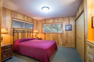 a bedroom with a bed and wooden walls at Yosemite's Riverfront Retreat in Wawona