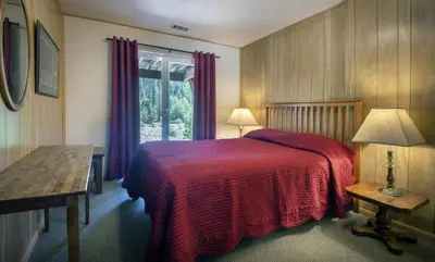 a bedroom with a bed with a red blanket and a window at Yosemite's Riverfront Retreat in Wawona
