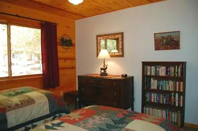 a bedroom with two beds and a book shelf with books at 9N Fox Hollow in Wawona