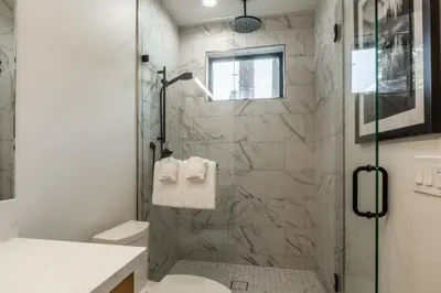 a white bathroom with a shower and a toilet at New Luxury 4BR /3BA Obsidian Reserve #110 – Hot Tub, 2-Car Garage, Pool Table, Mount Views! in Mammoth Lakes