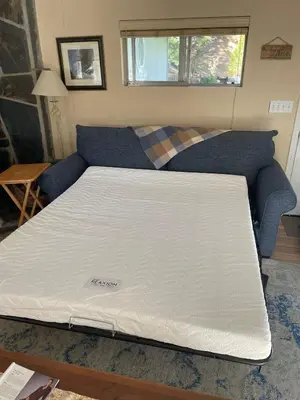 a bed in a room with a blue couch at Near Yosemite Bass Lake Cabin with Hot Tub, Lake View, Pet Friendly in Bass Lake